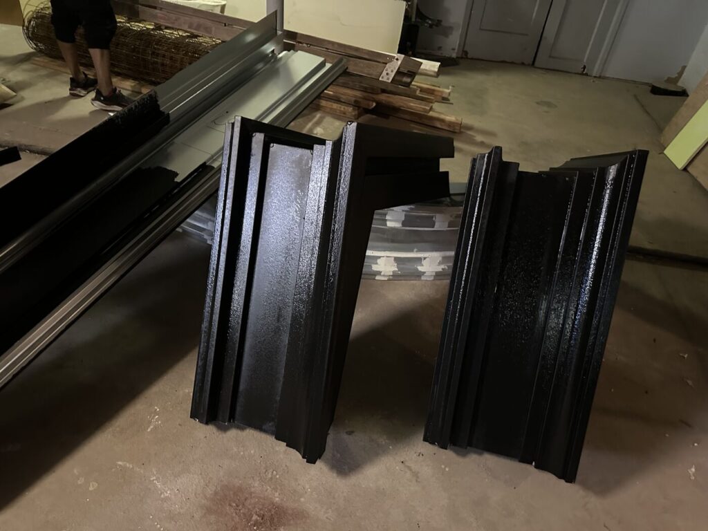 Black painted architectural trim and molding pieces prepared for installation during a building renovation.