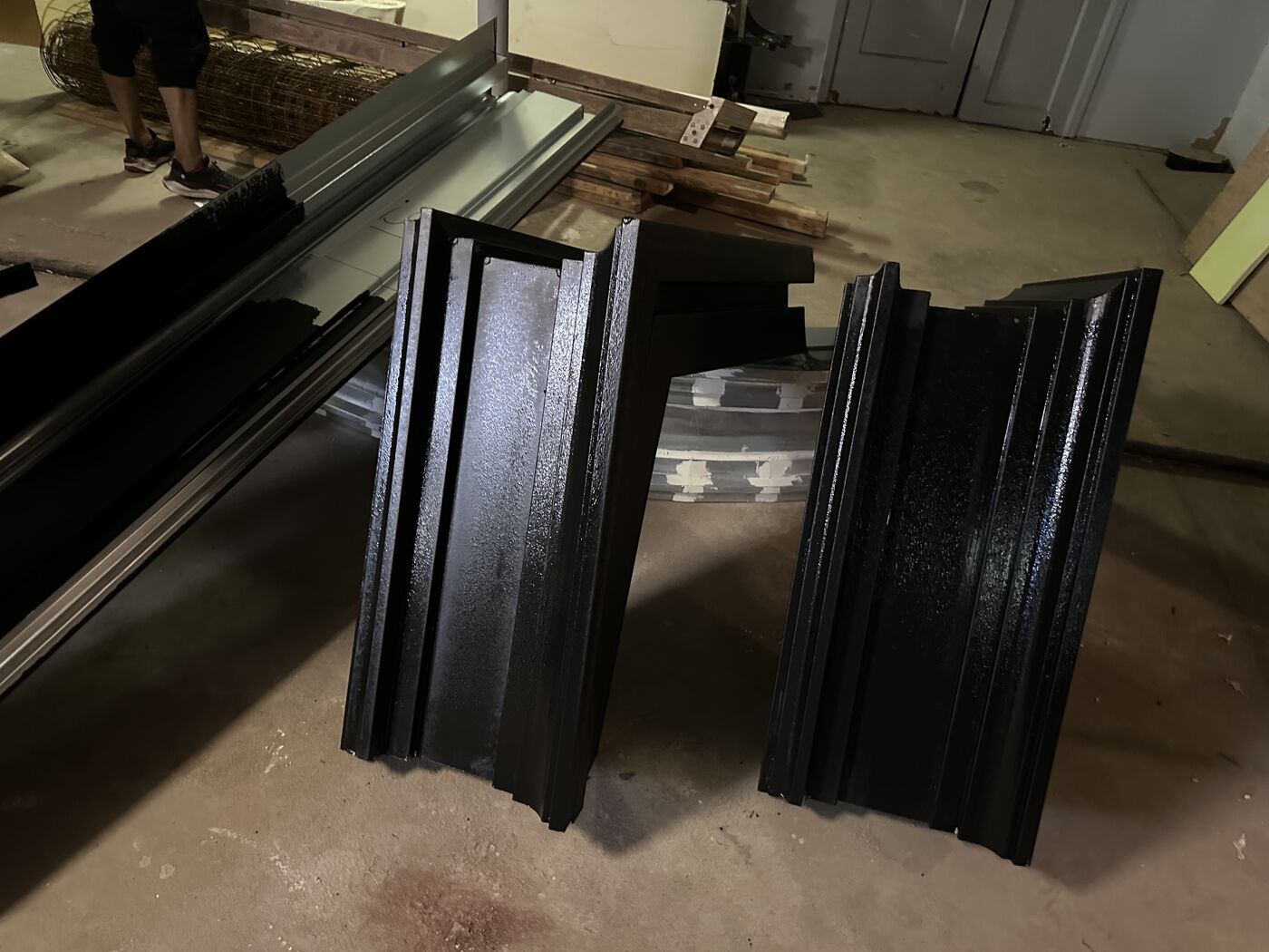 Black painted architectural trim and molding pieces prepared for installation during a building renovation.